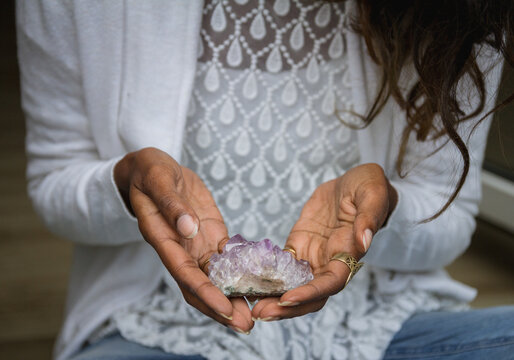 Unrecognizable ethnic female in casual outfit sitting with crystals for rituals