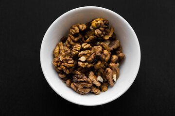 Walnut in a small plate on a black table. Walnuts is a healthy vegetarian protein nutritious food. Natural nuts snacks.