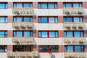 Worker washes windows in an office building. Washing the facade of an industrial building.