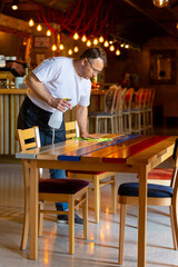 Waiter Cleaning the Table with Disinfectant Spray in a Restaurant