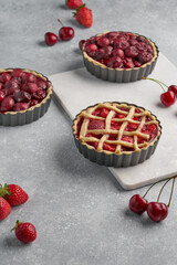vegan tartlets with cherries and strawberries on a light gray background and marble board