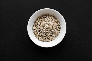 Sunflower seeds in a small plate on the black table. Healthy vegetarian protein nutritious food.