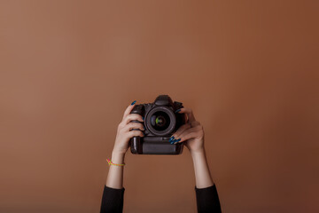 Photographer girl shooting images. Woman hands holding camera taking photos. Vivid brown...