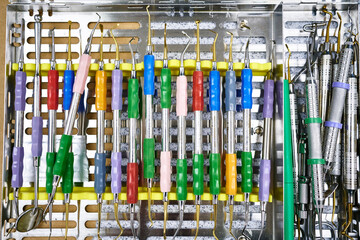 Top view of kit of clean curettes with colorful handles placed on metal tray in laboratory