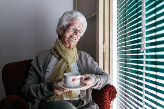 Aged woman with cup of tea staying at home during quarantine