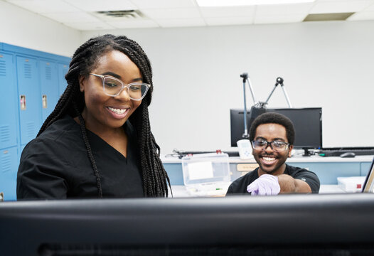 Black women and man in uniform discussing data on computer while working in contemporary laboratory together