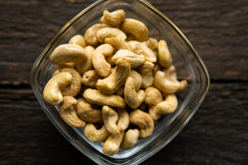 Cashew nuts in a small plate on a vintage wooden table as a background. Cashew nut is a healthy vegetarian protein nutritious food.