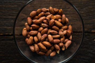 Peanut nuts in a small plate on a vintage wooden table. Peanuts nut is a healthy vegetarian protein nutritious food.