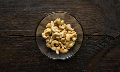 Cashew nuts in a small plate on a vintage wooden table as a background. Cashew nut is a healthy vegetarian protein nutritious food.