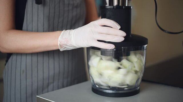 Woman hands cooking in a food blender. Chopped onions in a food processor.