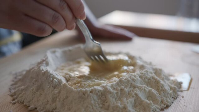 Close Up. Woman Mixing eggs into Flour, Making Dough at Home in a Kitchen. Slow Motion
