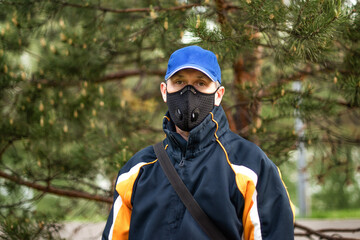 A man wearing respirator mask and a cap outdoors.