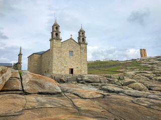 Fototapeta na wymiar Nosa Senora of Barca Church on the ancient sacral stones of rocky cape. Beach in Muxia, Galicia, Spain