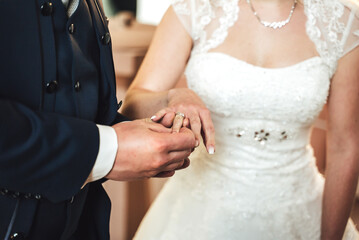 Close up of groom putting wedding ring on bride's finger. Bride and groom holding hands at wedding ceremony. Wedding rings on newlyweds hands.