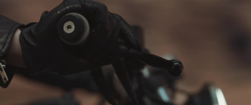 EXTREME CU Vintage custom motorcycle riding fast on a desert mountain road, focus on a handlebar
