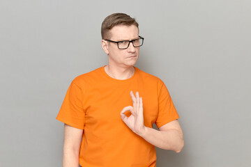 Portrait of serious confident man showing okay gesture with fingers