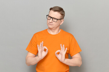 Portrait of serious confident man showing okay gestures with fingers