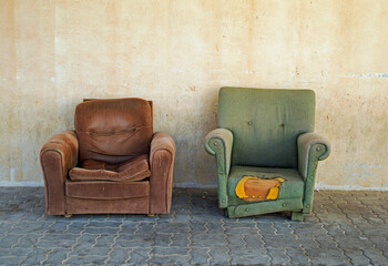 Two dilapidated arm chairs abandoned on the street