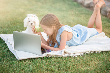 Little girl outdoors in the park with computer