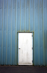 Obraz na płótnie Canvas Weathered exterior pale blue textured wall with white door for background