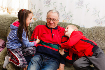 Obraz premium grandfather spends time with grandchildren in the living room