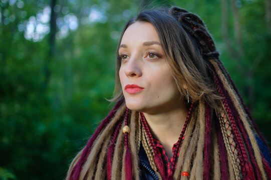 Outdoors portrait of a sensual girl with long dreadlocks in a city park or forest during evening or early morning, be different, alternative people concepts