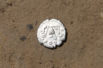 Fototapeta na wymiar Ancient silver coin in the sand