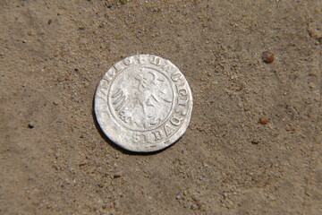 antique silver european coin on the sand