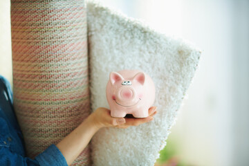 Closeup on woman with white carpet showing piggy bank