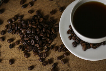 White coffee cup and coffee beans on wooden table with copyspace for text. Selective focus.