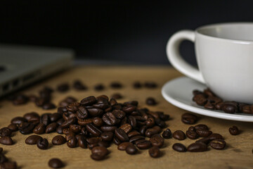 White coffee cup and coffee beans on wooden table with copyspace for text. Selective focus.
