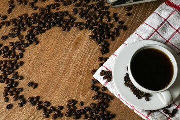 White coffee cup and coffee beans on wooden table with copyspace for text. Selective focus.