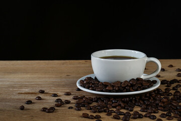 White coffee cup and coffee beans on wooden table with copyspace for text. Selective focus.