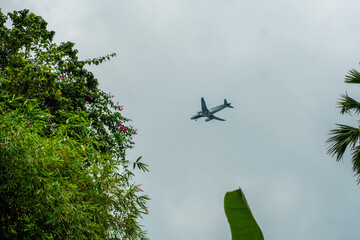Plane flying in a cloudy sky and preparing to land on a tropical island.