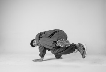 A man hip hop dancer or bboy freezes in one pose on a white background. Bboy doing stylish stunts.