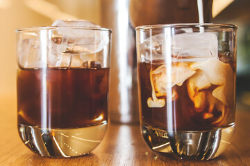 iced coffee and milk glass with ice cubes at wood table
