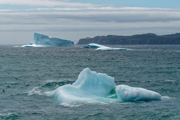 An iceberg grounded Port Rexton, Newfoundland, showing the beauty of the coastline in summer. Very popular with tourist.