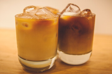 two glasses of iced coffee being at wood table