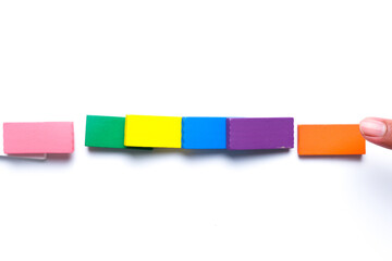 A picture of colourful dominoes been toppled on white background. A domino effect concept.