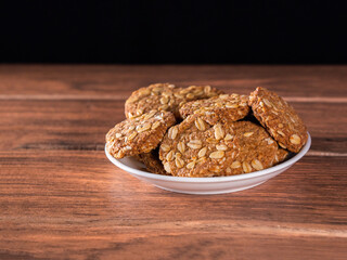many brown oatmeal cookies on a white plate on a wooden board