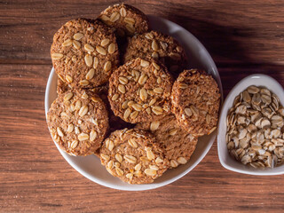many oatmeal cookies on a plate and fresh oats on the right top view