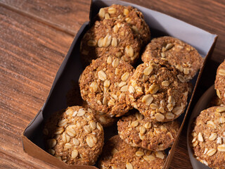 many oatmeal cookies in a brown cardboard box and on a plate close-up