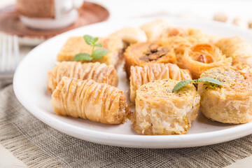 traditional arabic sweets (kunafa, baklava)  and a cup of coffee on a white wooden background. side view, selective focus.