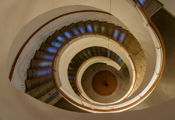 Spiral Staircase Leads Down Several Floors With Dramatic Lighting.