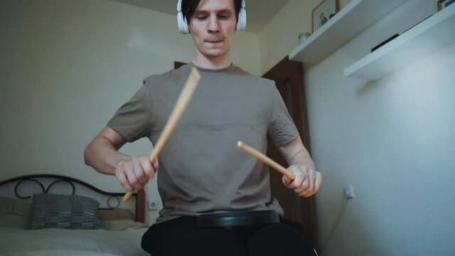 young drummer exercising with training plastic pad at home. Lessons for percussion instruments with metronome in 60 fps can be in slow motion