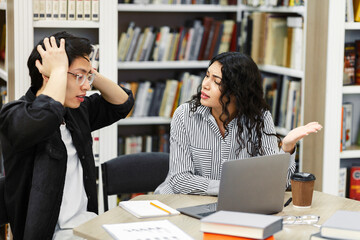 Stressed students preparing for examination in campus library