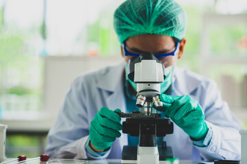 Scientists are looking at a microscopic to study and do research In order to produce therapeutic...