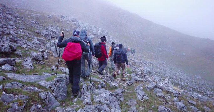 Group of hikers walking on a mountain at fogy morning