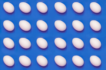 White eggs arranged on solid color background