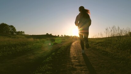 healthy beautiful girl is engaged in fitness, jogging, silhouette. free young woman is training in summer in park at dawn. Jogger girl breathes fresh air. evening run in beautiful rays of sun.